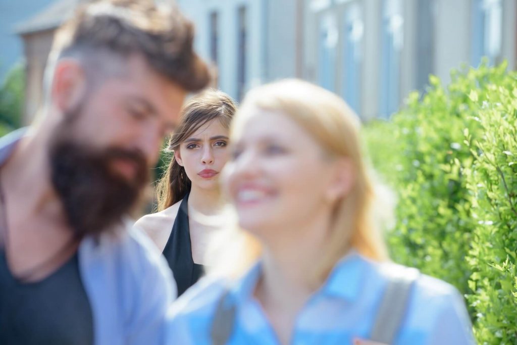 A woman looks disapprovingly at a man and a woman walking in front